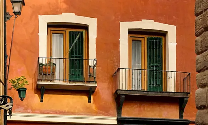 Una bandera española desgastada ondea orgullosamente en una calle empedrada de barrios históricos llenos de vida y color