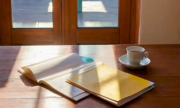 Una imagen de un libro escolar español colorido descansa sobre una mesa de madera junto a un tazón de café caliente