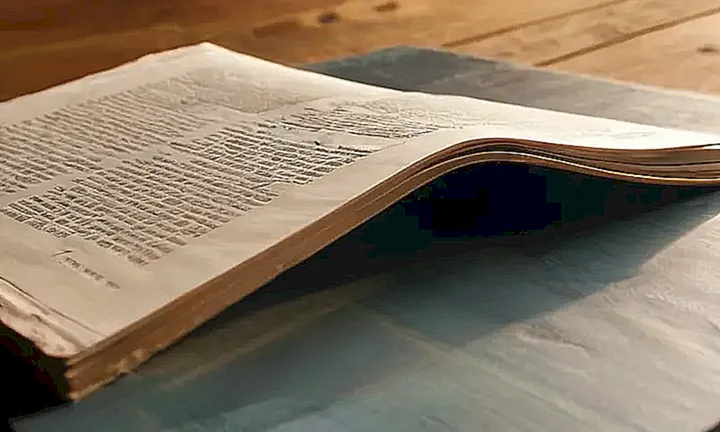 En la mesa hay un documento oficial doblado y un libro abierto en el fondo, con efectos de sombra y luz