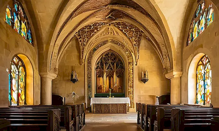 La iglesia tiene paredes de piedra rugosas, puertas de madera oxidada y un techo gótico adornado con detalles arquitectónicos intrincados y patrones geométricos