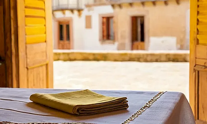 En una habitación iluminada por la tarde, un pasaporte español y un pañuelo de Galicia están colocados sobre una mesa con vista a una ventana pintoresca