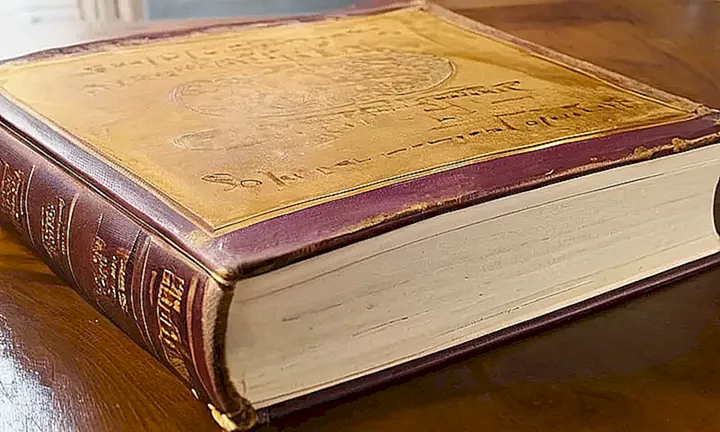 Un libro antiguo y de lujo descansa sobre una mesa de madera con un aspecto desgastado