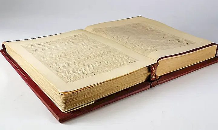Una vieja y amarilleada hoja de papel se encuentra en un escritorio rústico con una inscripción negra: Historia detrás del derecho de adquirir la nacionalidad española por apellidos
