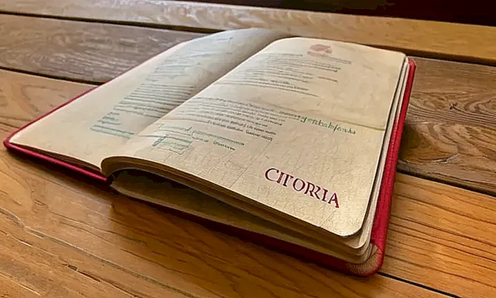Un pasaporte español dañado reposa en una mesa de madera con papel de guía sobre cómo obtener la nacionalidad española al lado