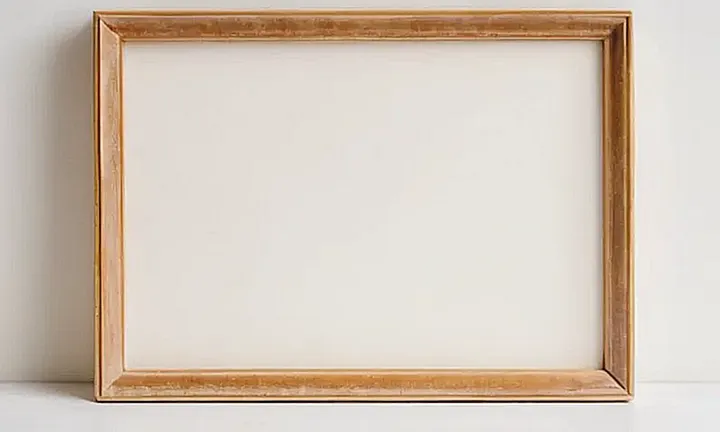 Una fotografía difusa sobre un fondo blanco con una moldura de madera en tono beige y ligeras imperfecciones
