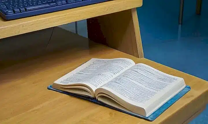 Un escritorio con características de uso regular y algún desgaste está iluminado suavemente por el sol que entra a través de la ventana