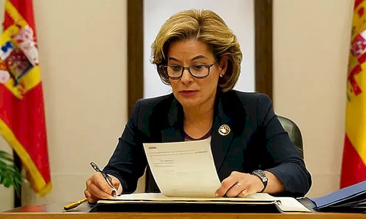 Una mujer y un funcionario del gobierno trabajan en una solicitud de nacionalidad española sentados ante un escritorio gubernamental