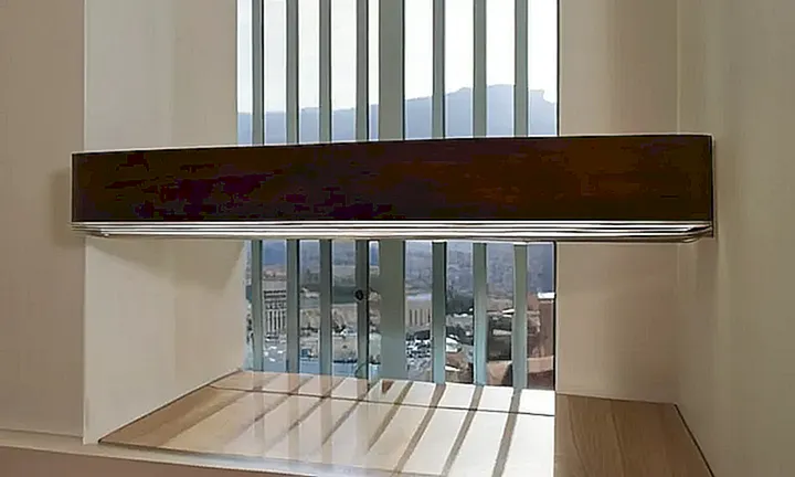 Una pantalla con suavemente iluminada está sobre una mesa en un espacio interior con una vista panorámica de la ciudad de Palma de Mallorca