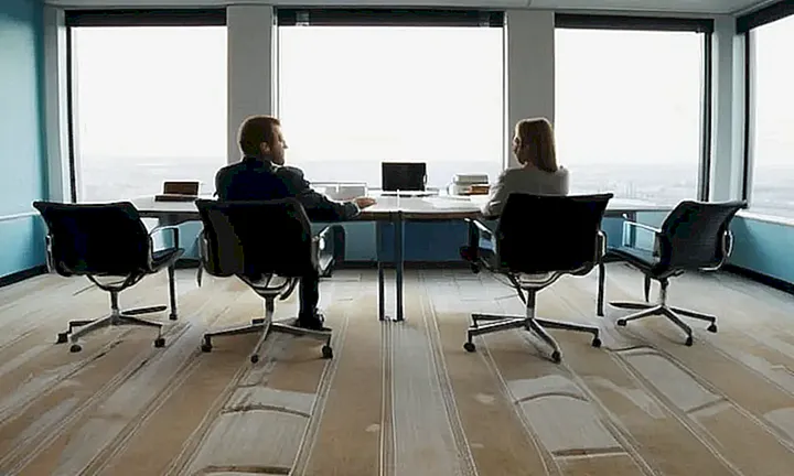 Una oficina gubernamental interior con muebles sencillos y una ventana que ofrece vista a la ciudad, llena de silencio y trabajo