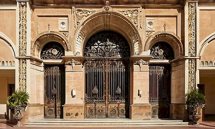 Un edificio municipal en Málaga muestra una fachada desgastada y sombreada con un arco de entrada bien trabajado