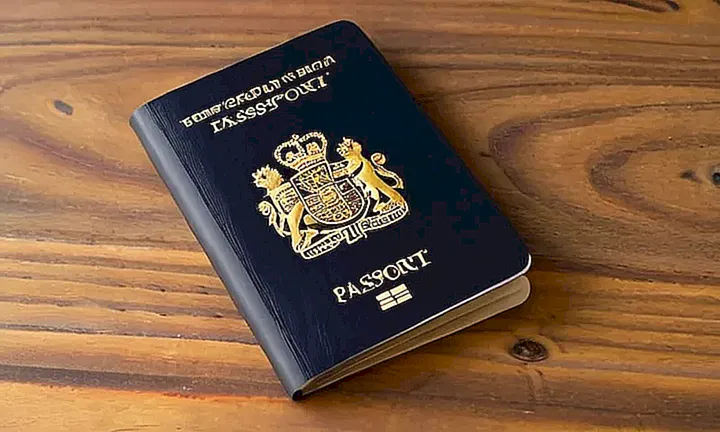 Una fotografía de un pasaporte con el escudo de España dorado en la cubierta y los rasgos de un hombre en la foto