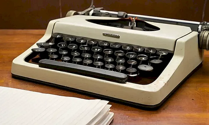 Una mesa de estudio desordenada con una vieja máquina de escribir y un texto en inglés arrugado