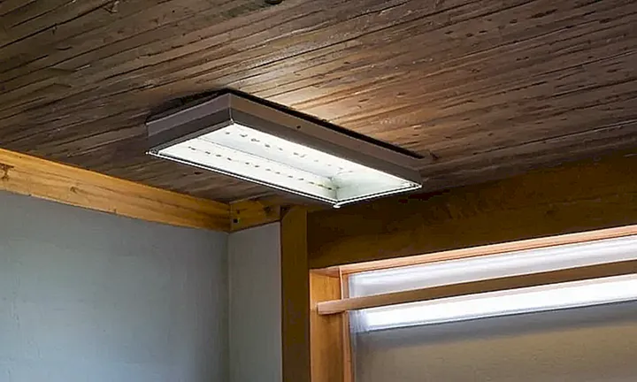 En un escritorio desgastado se encuentra una hoja de papel, ligeramente doblada, iluminada por una luz fluorescente que proyecta sombras suaves y grises