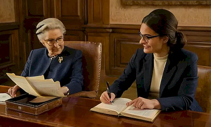 En una habitación oscura y acogida con luces LED suaves, un anciano y una mujer se sientan mientras él estudiaba un manual e ella mira el sitio web de la Corte Internacional de justicia