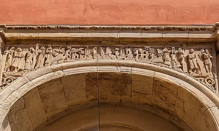 Un arco romano viejo y erosionado está adornado con un letrero español desgarrado y un puente de cuerda colgado entre dos estacas deterioradas