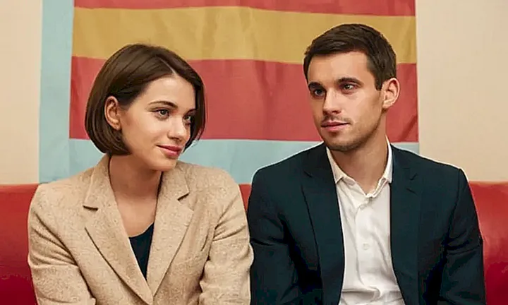Un joven adulto y su pareja se sientan en un sofá beige contemplando documentos de identidad