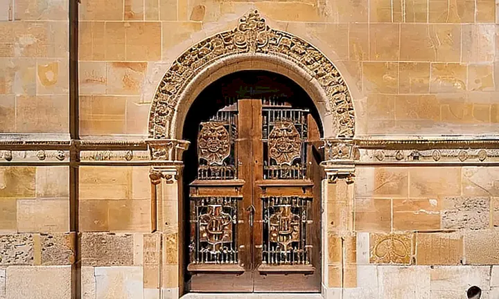 La fachada de un edificio histórico en Palma de Mallorca presenta detalles carnosos y ornaménticos, con una combinación suave de granito y piedra caliza
