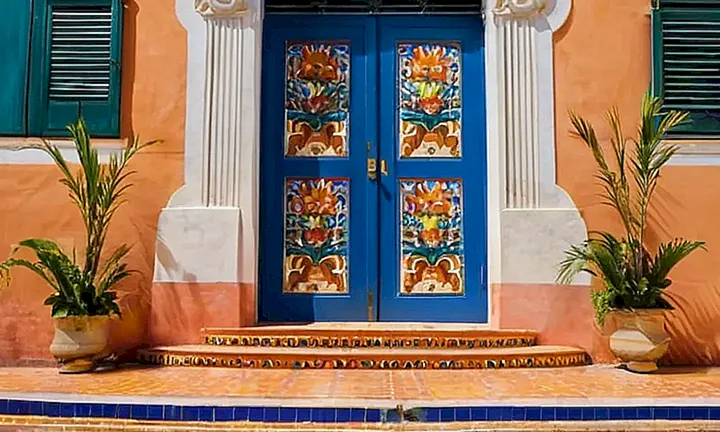 Una plaza cubana iluminada por el sol, con detalles arquitectónicos ornamentados y un paso gradual de alguien vestido con una guayabera clásica