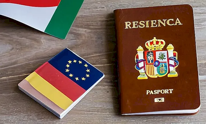 Un pasaporte gastado yace abierto sobre la mesa de madera gris, mostrando un logotipo español y una visa argentina