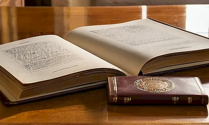 En una mesa de madera iluminada por la luz del sol se encuentra un viejo libro con tapa de cuero y una foto de pasaporte en el interior