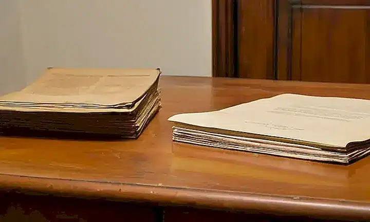 Una mesa de madera vieja y desgastada está adornada con documentos organizados y un título en oro que habla sobre la ciudadanía española