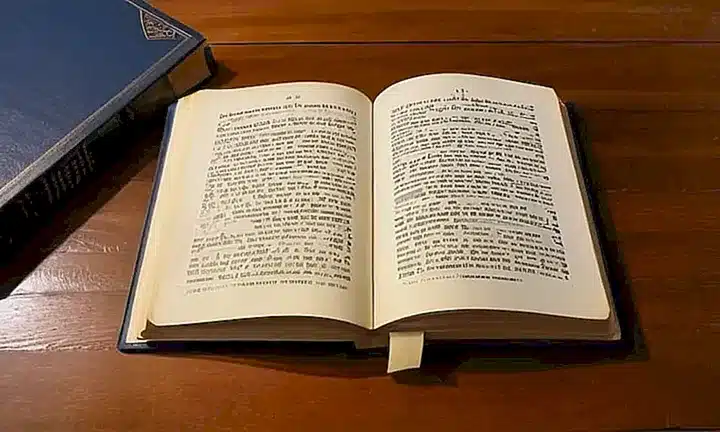 Un libro de tapa dura con una cubierta de cuero suave se encuentra abierto sobre una mesa bajo la luz del amanecer