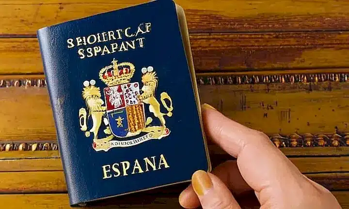 En una escritura desgastada por el uso, un estudiante española prepara su pasaporte de color verde y rojo para salir del país
