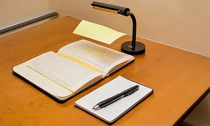 Un escritorio minimalista adornado con elementos de uso evidente: un ordenador, una impresora y un libro