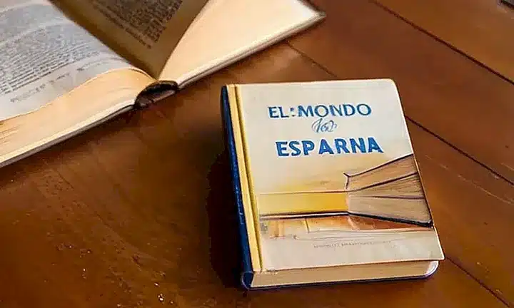 Un libro de tapa dura desgastada titulada Ventajas de ser ciudadano español en Argentina reposa en una mesa claramente desordenada
