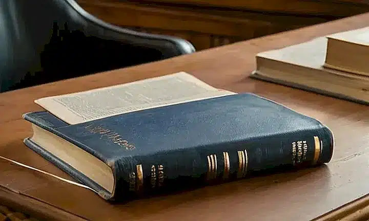 Una vieja libreta de cuero descansa abierta sobre una mesa de madera, iluminada por el sol que entra a través de la ventana