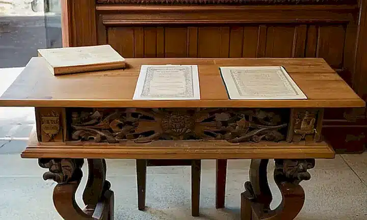 Una habitación con muebles antiguos y documentación oficial rodeada de detalles cotidianos en un entorno urbano