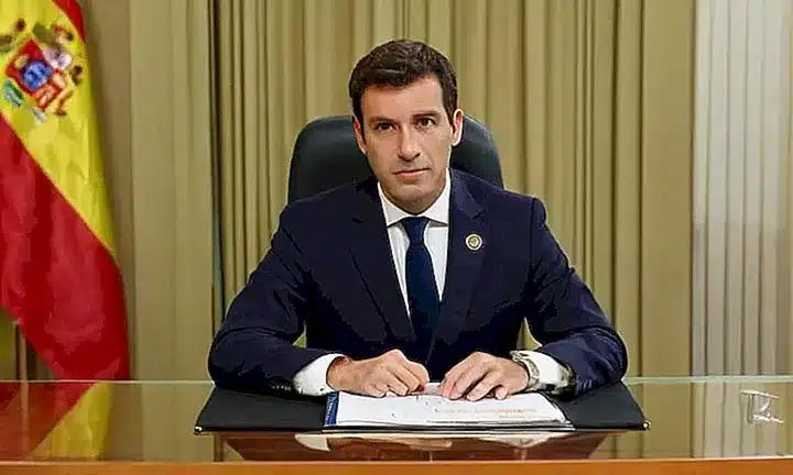 Un funcionario español de Justicia se sienta en una mesa minimalista y moderna, rodeado de un ambiente agradable iluminado por la luz natural