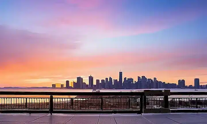 La portada del libro muestra un paisaje urbano al atardecer en tonos pastel sobre un fondo azul