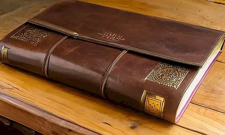 En una mesa antigua y desgastada se encuentra un cajón abierto lleno de documentos amarillentos
